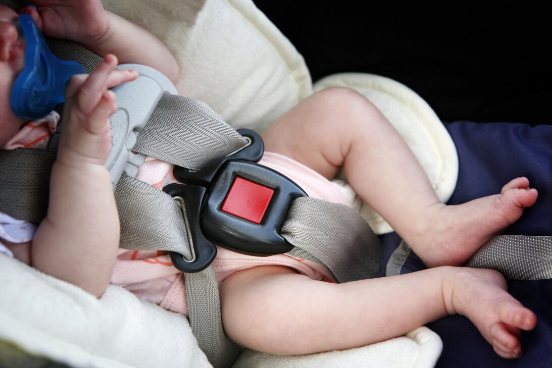 Un bebé amarrado a una silla infantil en un vehículo.