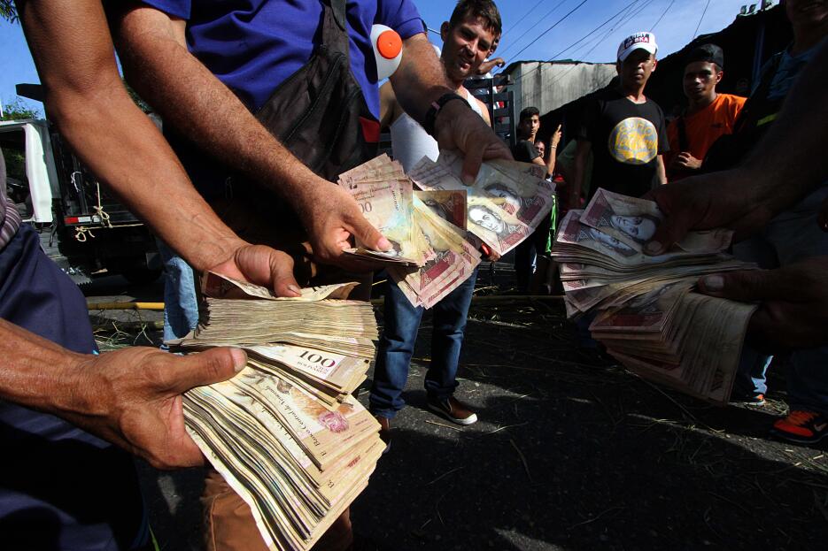 Un grupo de manifestantes muestra los billetes inservibles de 100 bolíva...