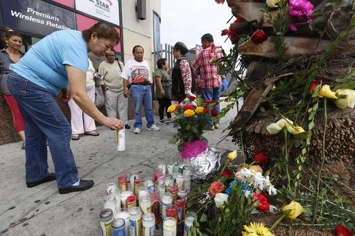 Una mujer deposita una vela en el altar calljero por las víctimas.